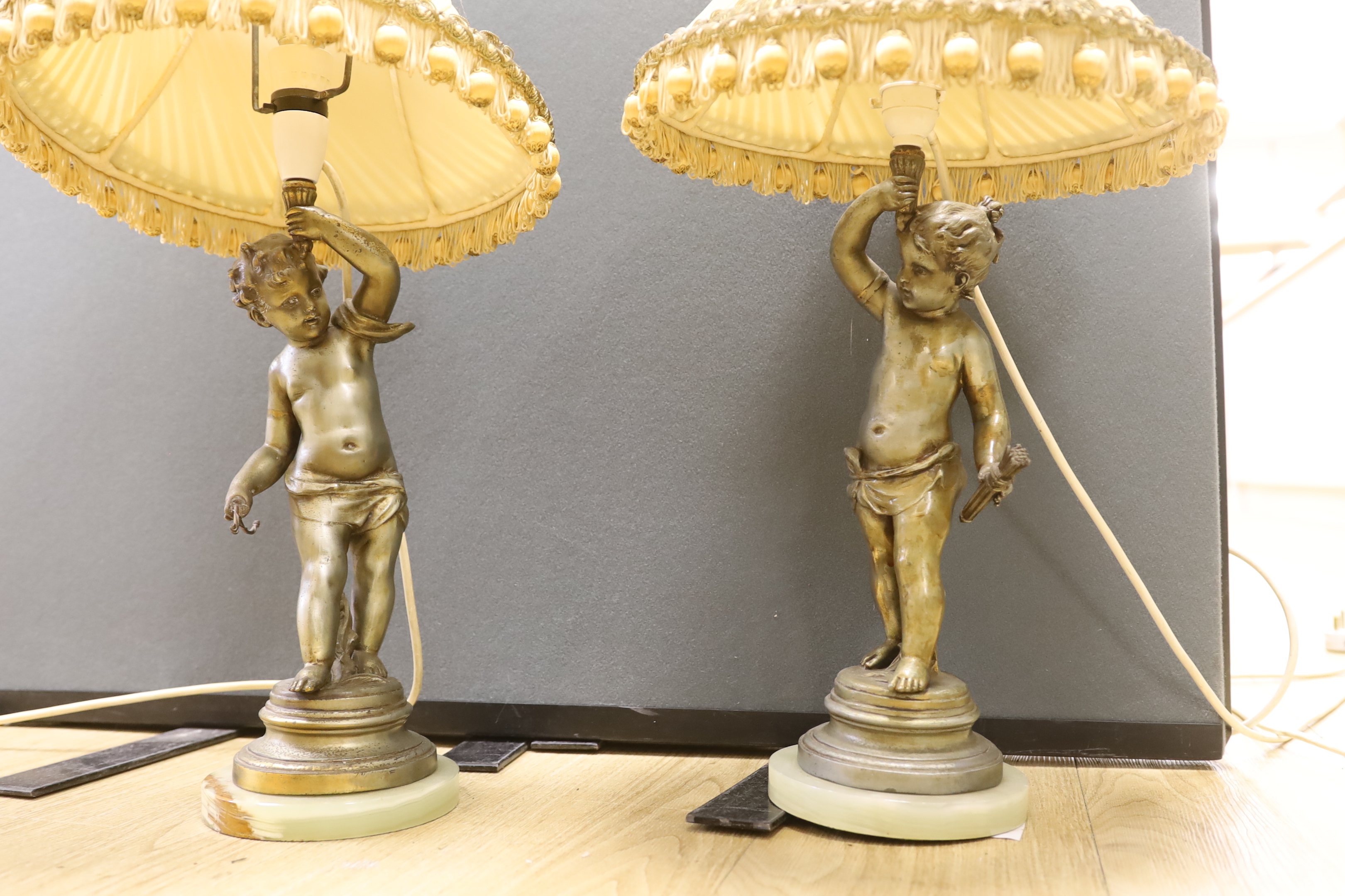 A pair of early 20th century spelter ‘cherub’ table lamps with shades, 63cm total